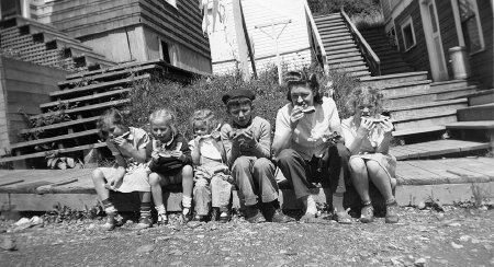 Kids sitting on a boardwalk, eating watermelon